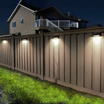 Residential fence perimeter illuminated by evenly spaced LED wall lights providing security and accent lighting