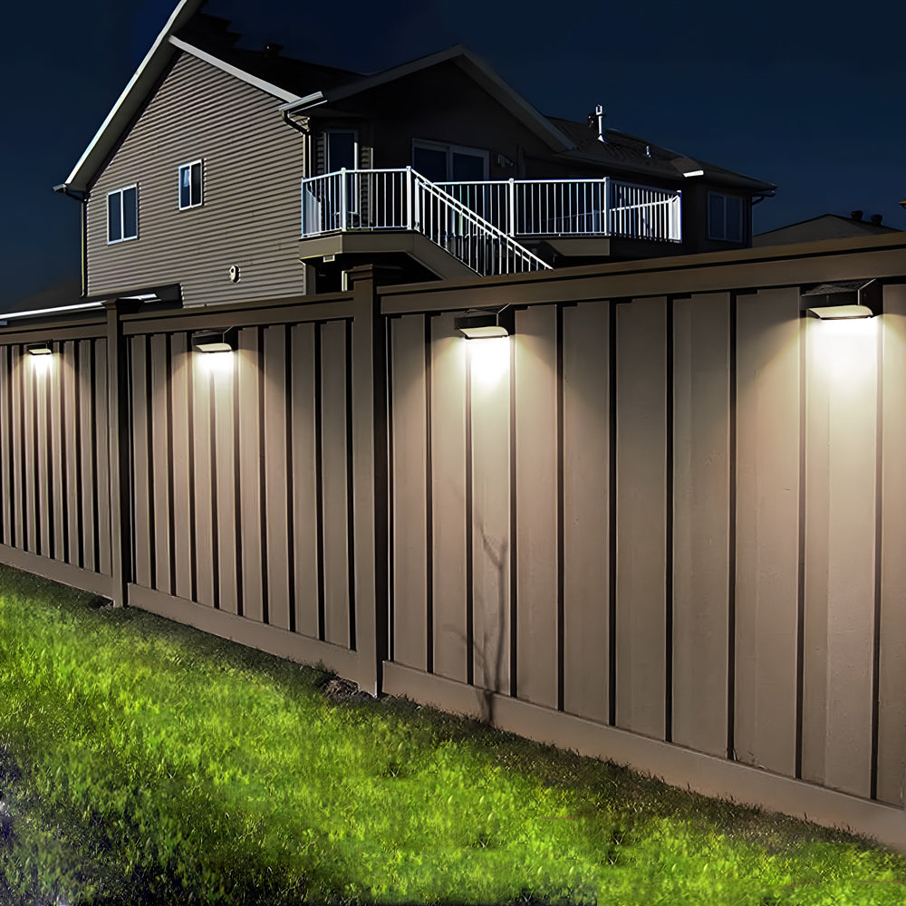 Residential fence perimeter illuminated by evenly spaced LED wall lights providing security and accent lighting