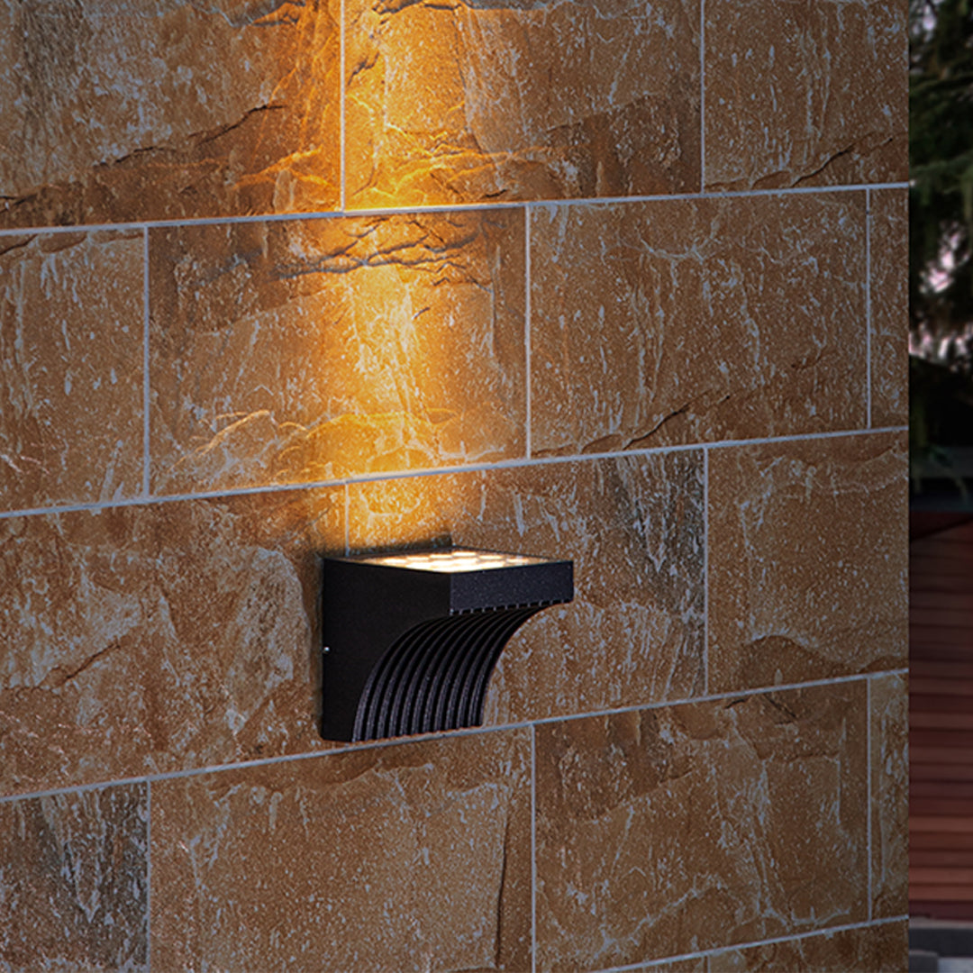 Close-up view of bronze outdoor light fixture showing curved arm and mounting details