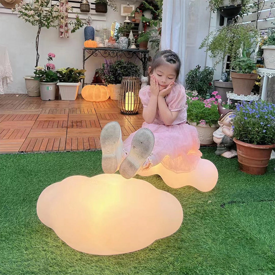 Child playing on grass beside glowing organic-shaped outdoor light fixture during golden hour