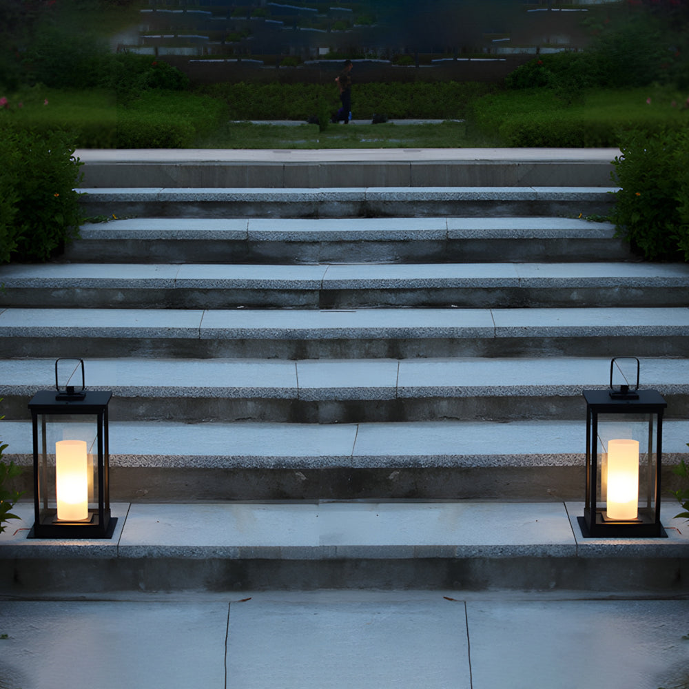 Two matching outdoor lanterns with LED candles illuminating concrete steps during twilight hours