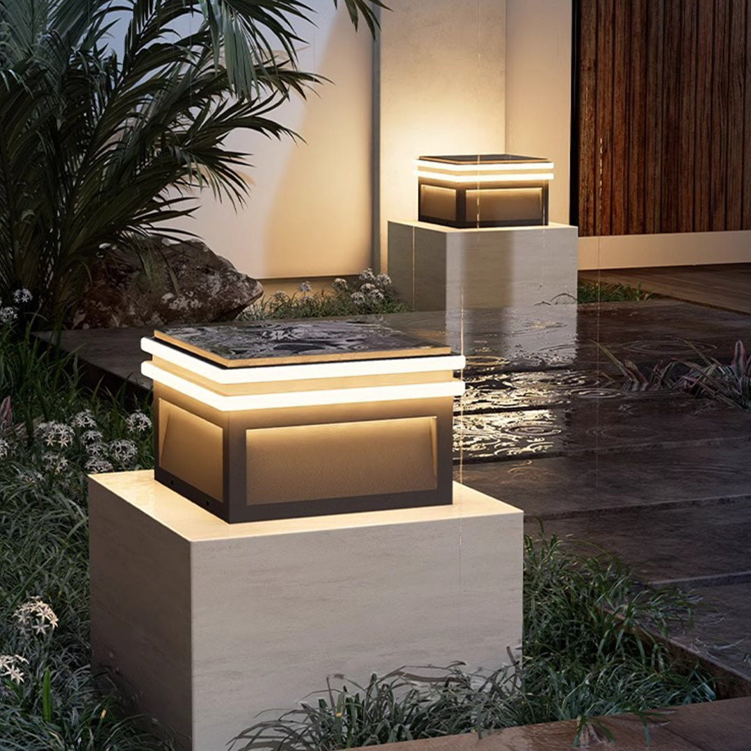 Modern cube post lights illuminating contemporary residential patio area with warm ambient lighting at evening