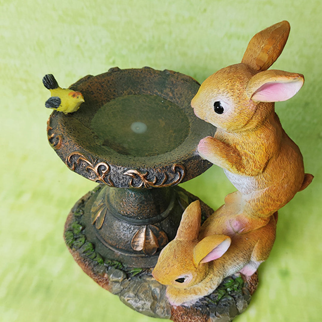 Family of rabbits around illuminated fountain creating whimsical garden water feature display