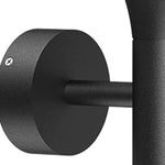 Modern black dome wall light with extending arm illuminating brick exterior wall at dusk
