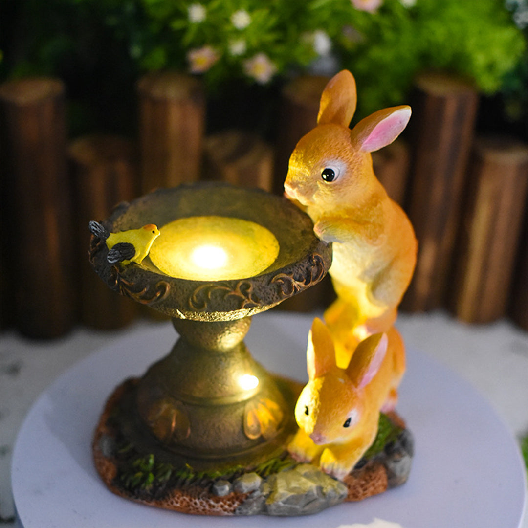 Rabbit fountain ornament with warm LED lighting creating magical ambiance in outdoor setting