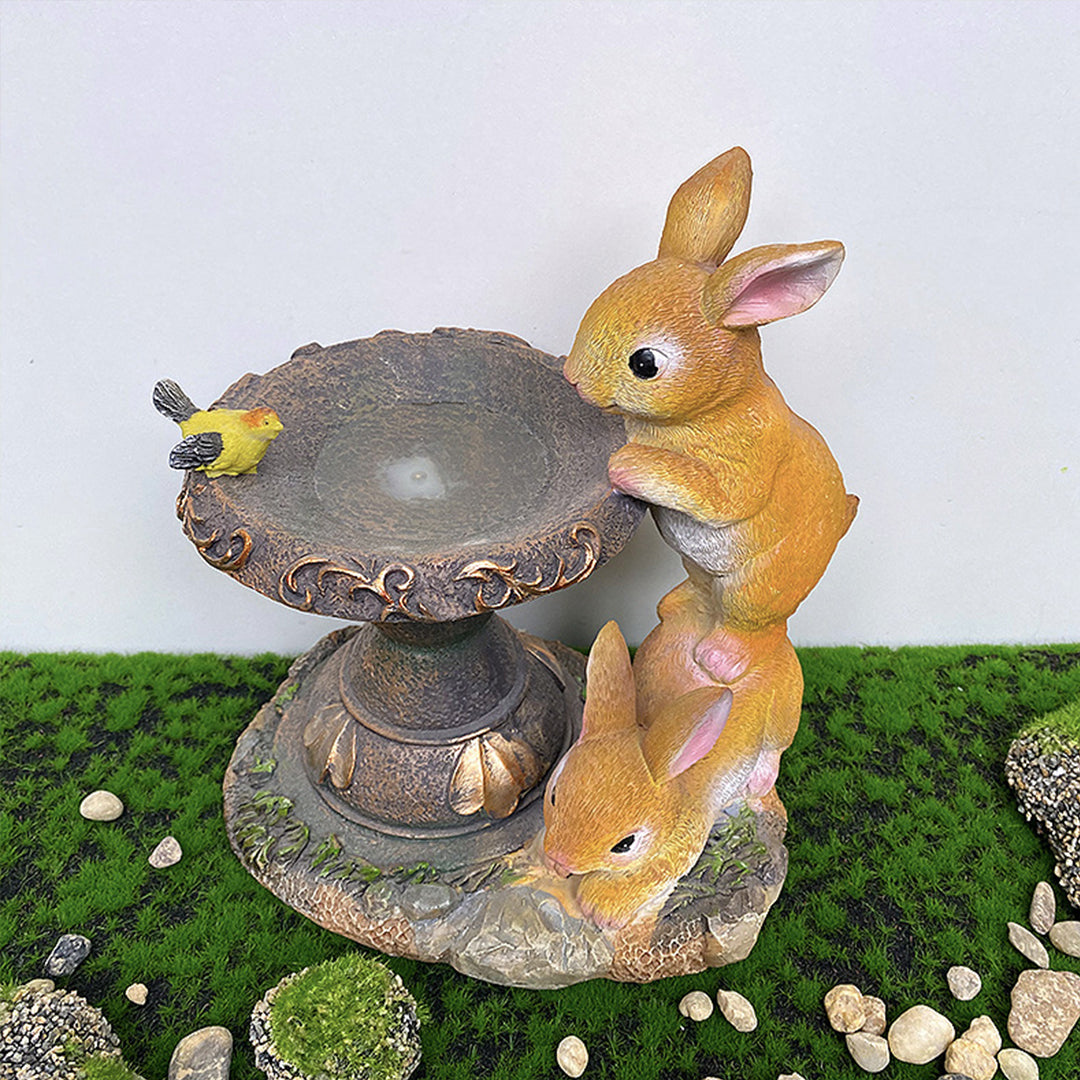 Rabbit fountain ornament positioned on moss surface with small decorative pebbles around base