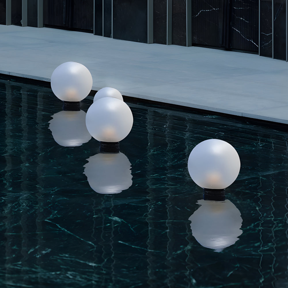 Floating sphere lights creating magical ambiance on dark water surface with reflective illumination