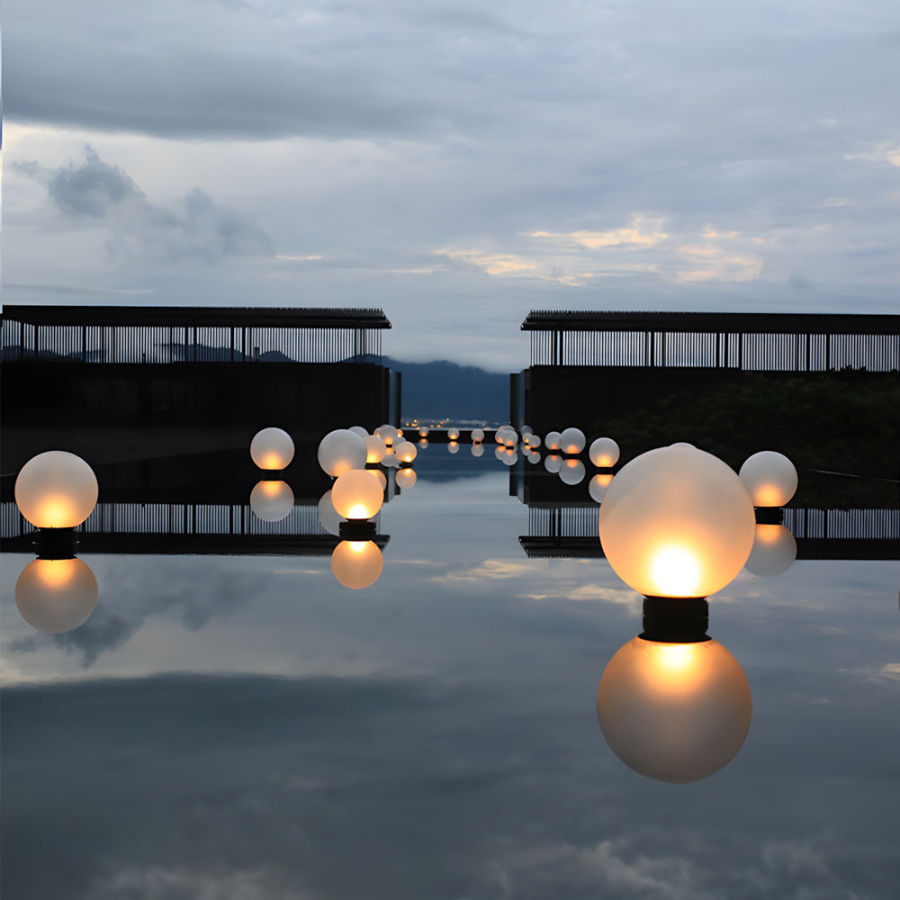 Waterproof sphere lights floating on lake surface near wooden dock during twilight hours