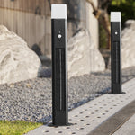 Pair of black solar post lights with motion sensors installed on concrete pathway