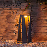 Sculptural outdoor lighting fixture illuminating textured brick wall in evening setting