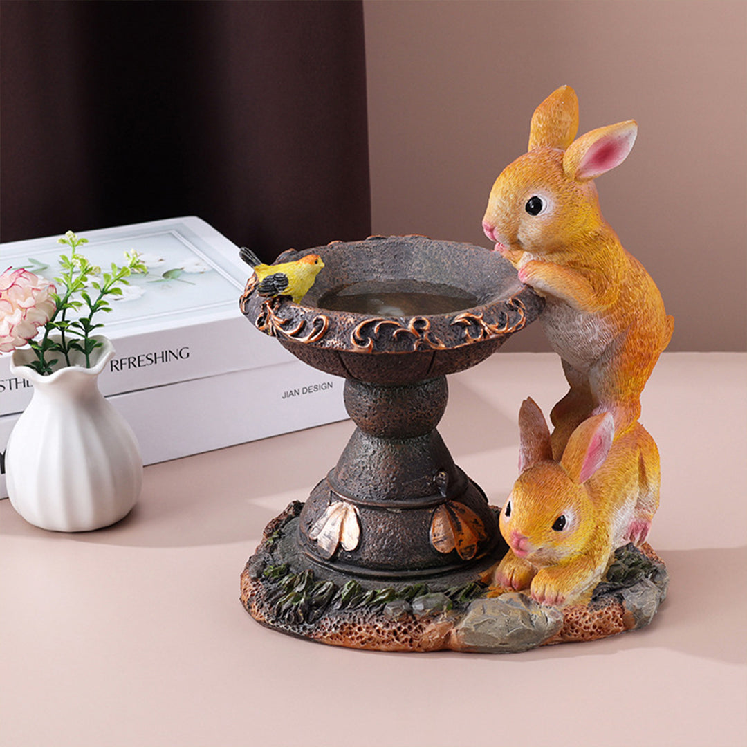 Multi-rabbit fountain display with ornate water basin and butterfly accents on neutral background