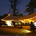 Outdoor camping setup with solar LED strips providing warm illumination for evening activities