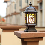 Classic outdoor pillar light with ornate metalwork and warm yellow glow in residential setting