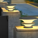 Multiple contemporary post lights installed on concrete barriers creating evening pathway illumination