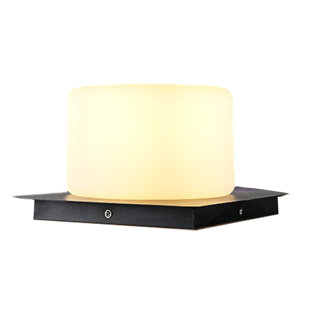 Cylindrical LED light fixture with warm glow positioned on sleek black rectangular base