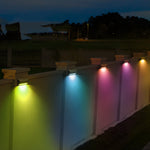 Colorful LED wall lights creating vibrant rainbow spectrum illumination along modern fence structure at night