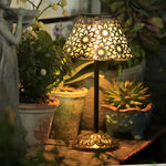 Outdoor dining setup enhanced by solar table lamp casting intricate light patterns across potted plants