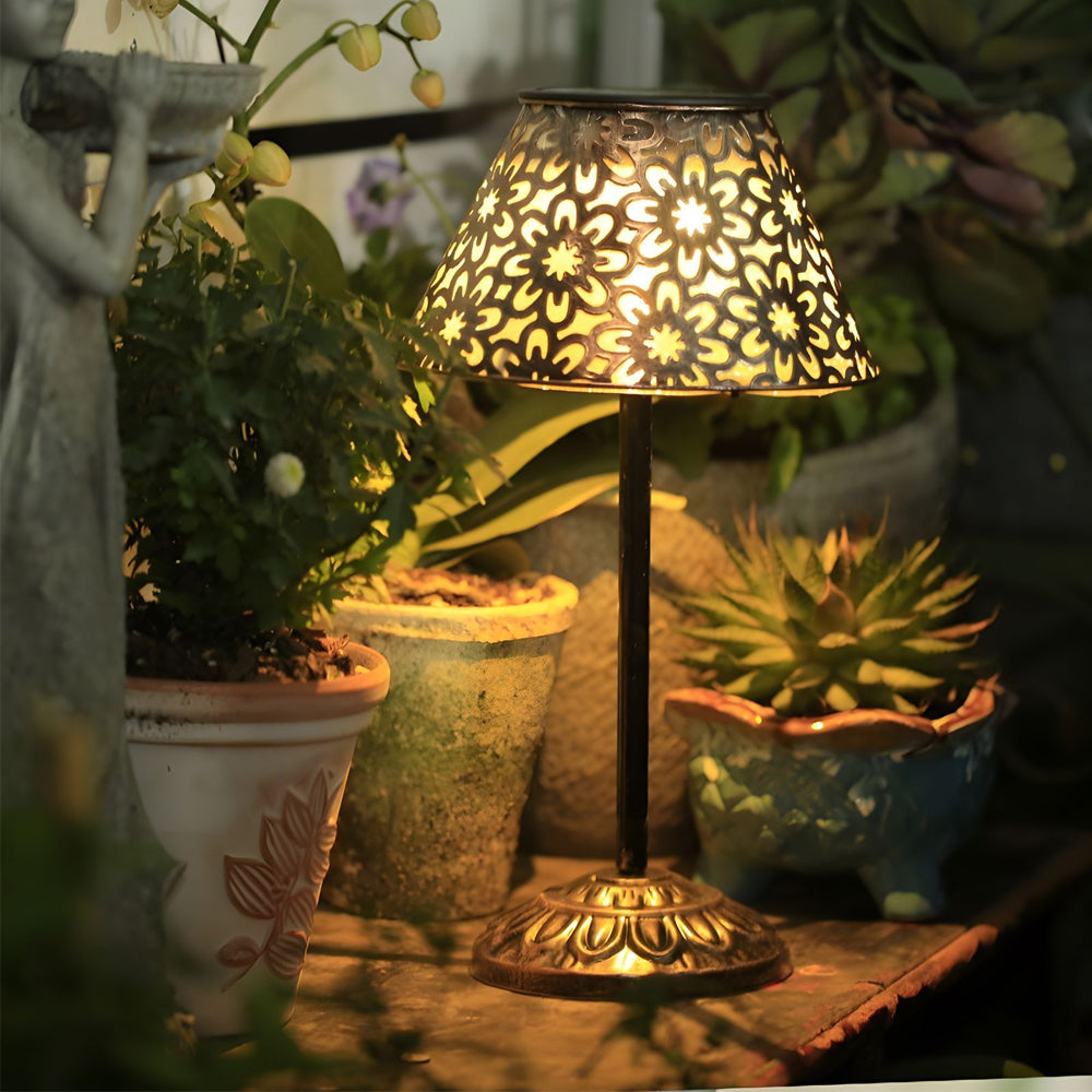 Outdoor dining setup enhanced by solar table lamp casting intricate light patterns across potted plants