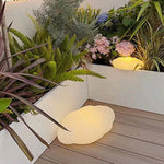 Modern cloud-shaped outdoor light creating soft illumination among tropical plants on patio