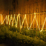 Wooden fence illuminated by continuous solar LED strip creating dramatic zigzag pattern