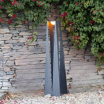 Sleek geometric lantern placed in garden setting with natural stone and flowering plants