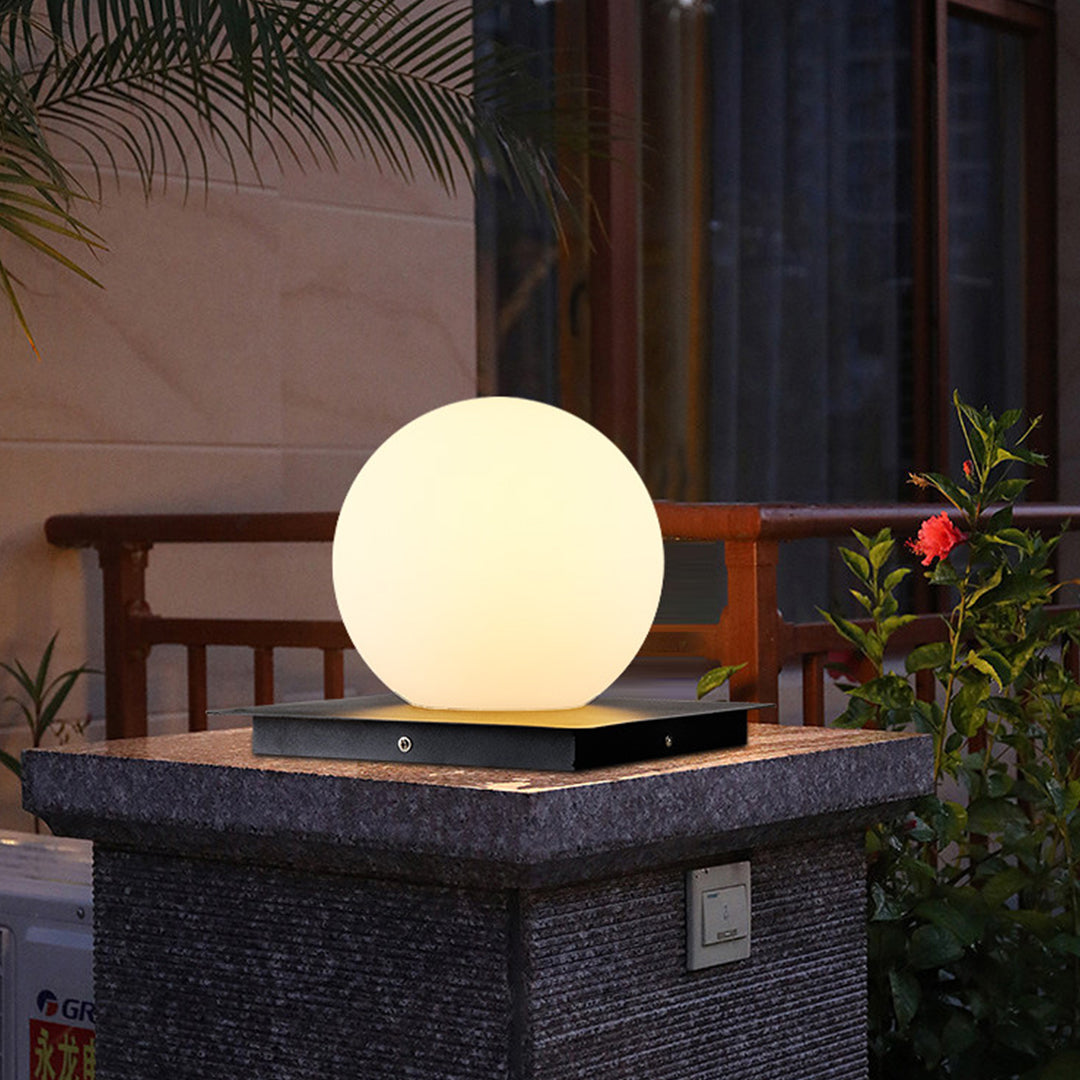 Glowing sphere lamp creating ambient lighting on woven outdoor furniture during evening patio setting