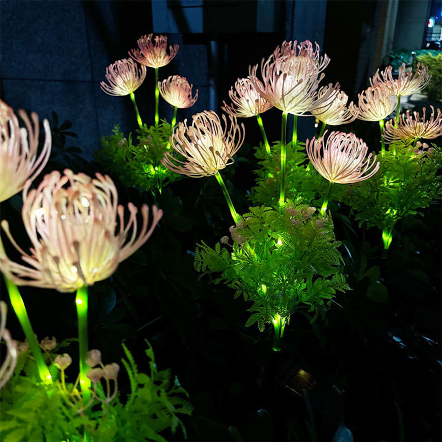 Collection of illuminated solar flower lights with warm LED glow scattered across garden landscape