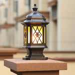 Pair of matching post cap lights with traditional styling positioned on wooden fence pillars