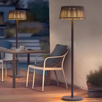 Tall outdoor floor lamp with natural fiber shade creating warm ambient lighting on modern patio
