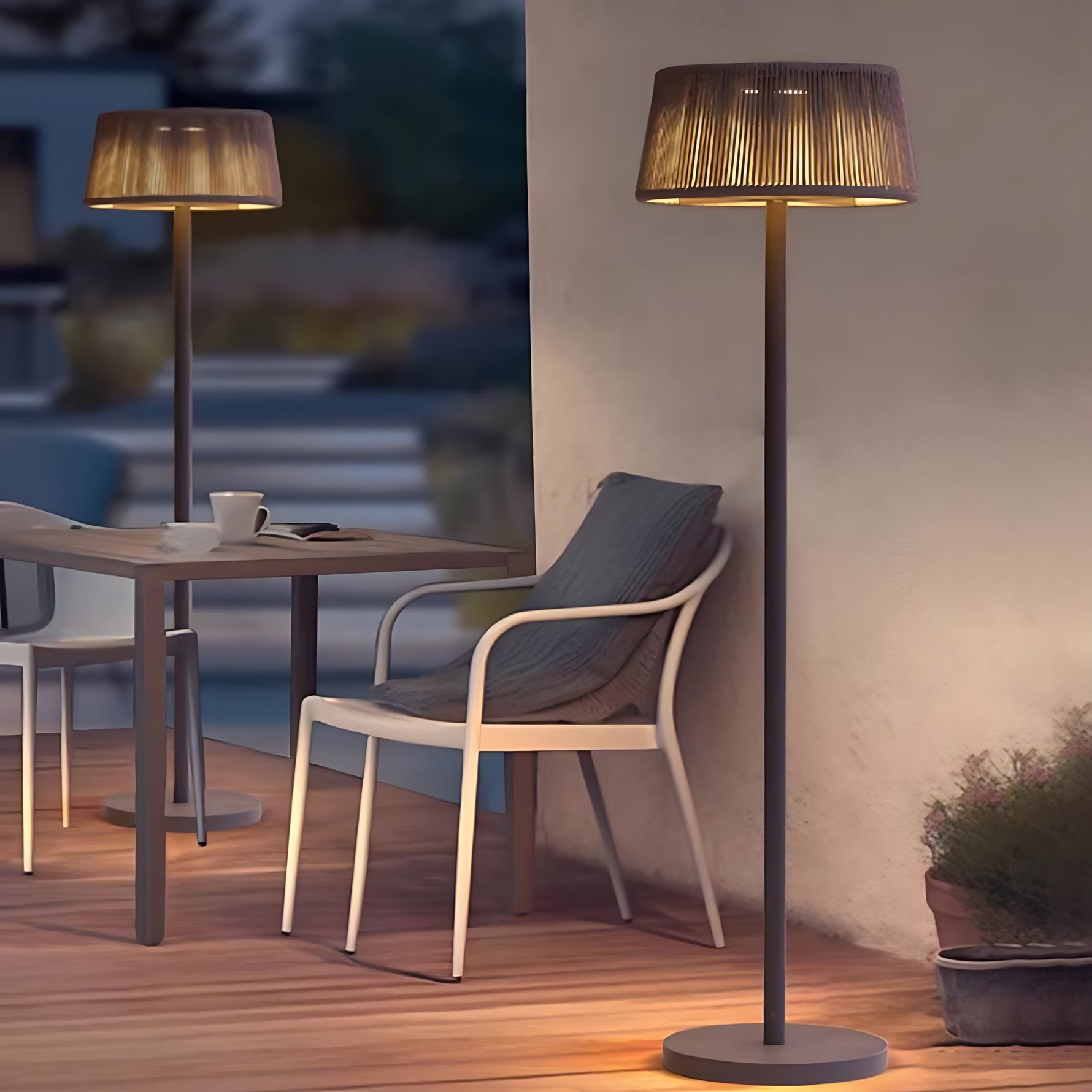 Tall outdoor floor lamp with natural fiber shade creating warm ambient lighting on modern patio