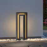 Single tall bollard light positioned near modern patio with decorative white stones