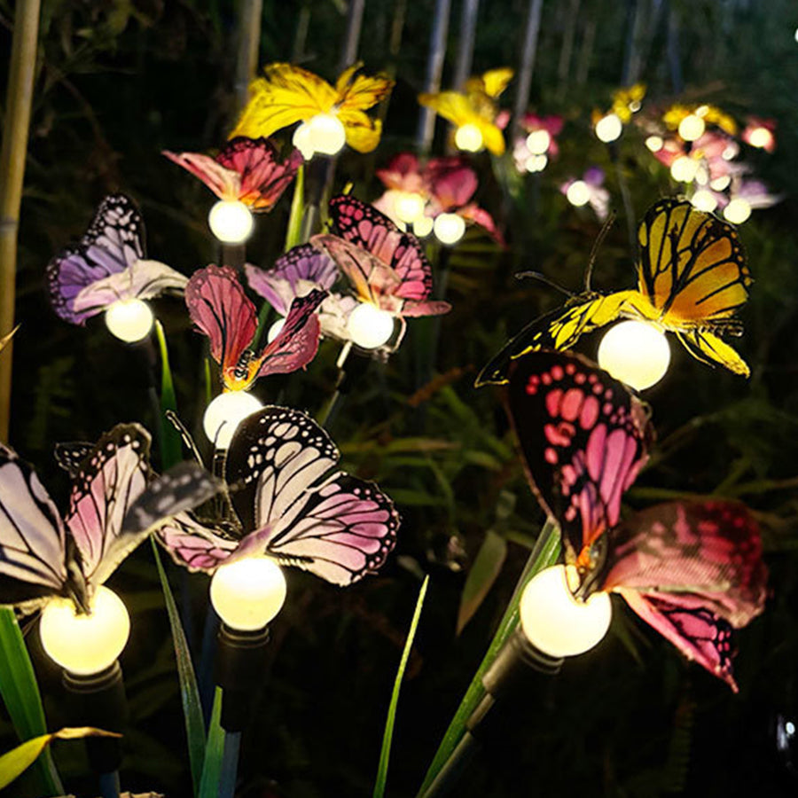 Pink and yellow butterfly solar lights glowing softly in nighttime garden environment