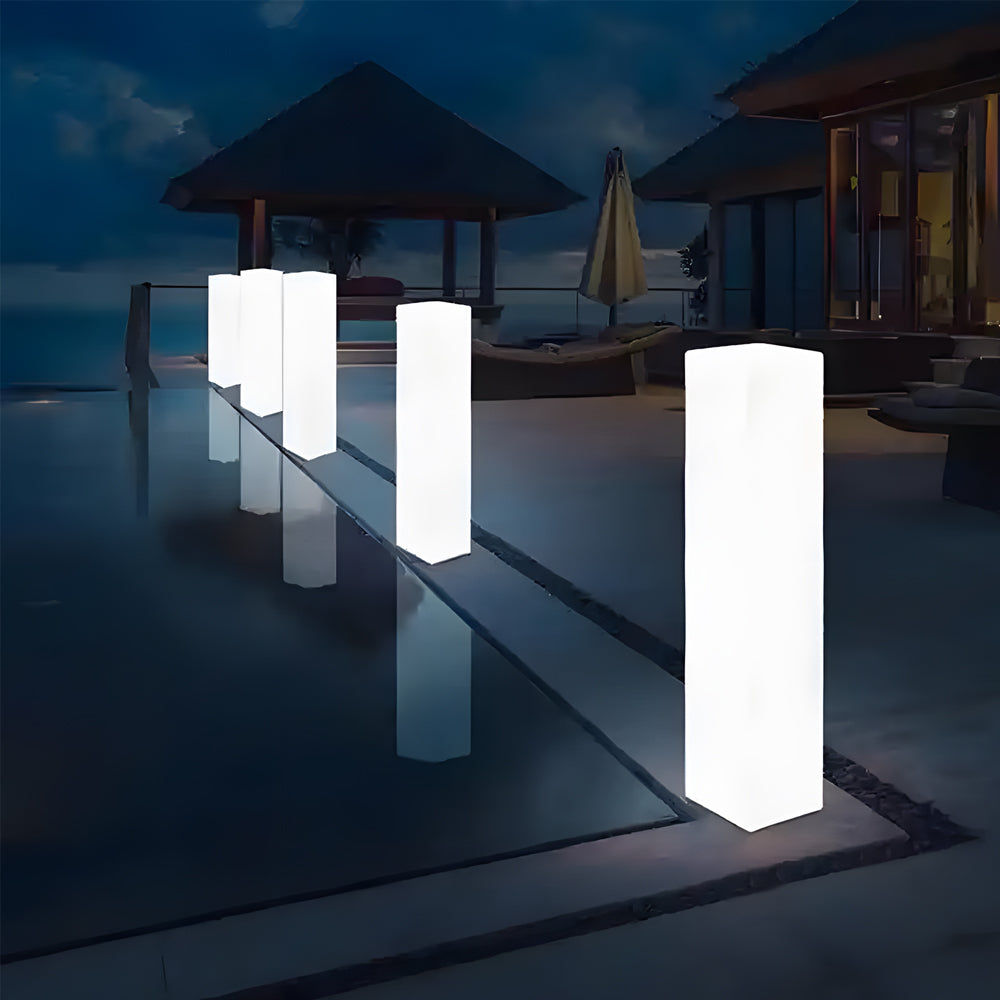 Contemporary illuminated pillar lights creating ambient lighting around modern poolside deck at twilight