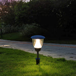 Solar garden light illuminating green grass area with warm LED glow during evening hours