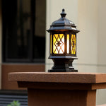 Vintage-inspired post cap lantern with crosshatch glass design illuminated on wooden pillar
