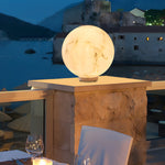 Waterfront terrace setting with large moon sphere lamp providing dramatic ambient lighting