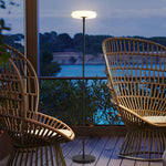 Wicker chair on deck with floor lamp by water