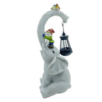 White elephant statue garden ornament holding black lantern with small bird perched on top