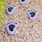 White footprint-shaped solar lights scattered on decorative pebbles during daytime for charging